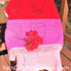 Filet crochet rose blanket pattern in red, hot pink, and light pink draped over an outdoor wooden chair