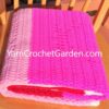 Folded filet crochet rose blanket in hot pink and light pink yarn on a wooden chair