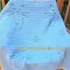 Light blue filet crochet cat blanket draped over wooden chair showing walking cats design