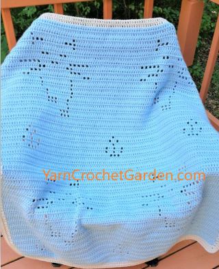 Light blue filet crochet cat blanket draped over wooden chair showing walking cats design