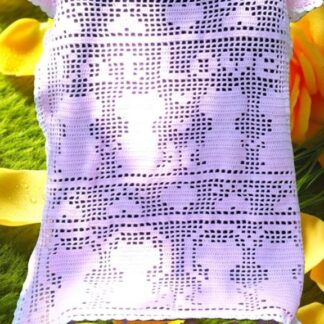 Finished cat filet crochet blanket with heart and paw motifs in a neutral yarn, shown as a living room throw.