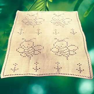 Finished filet crochet bee blanket displayed on a soft surface